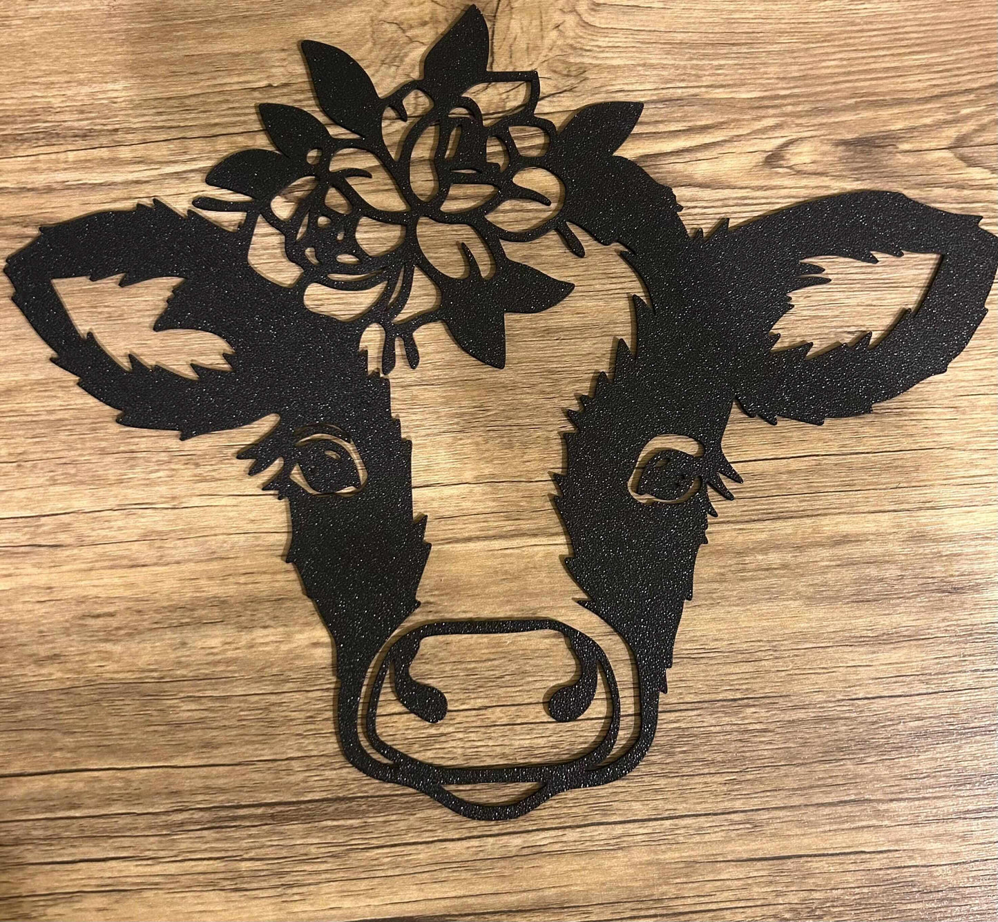 floral highland cow wall art design featuring a black cow head with floral accents on a wooden background.