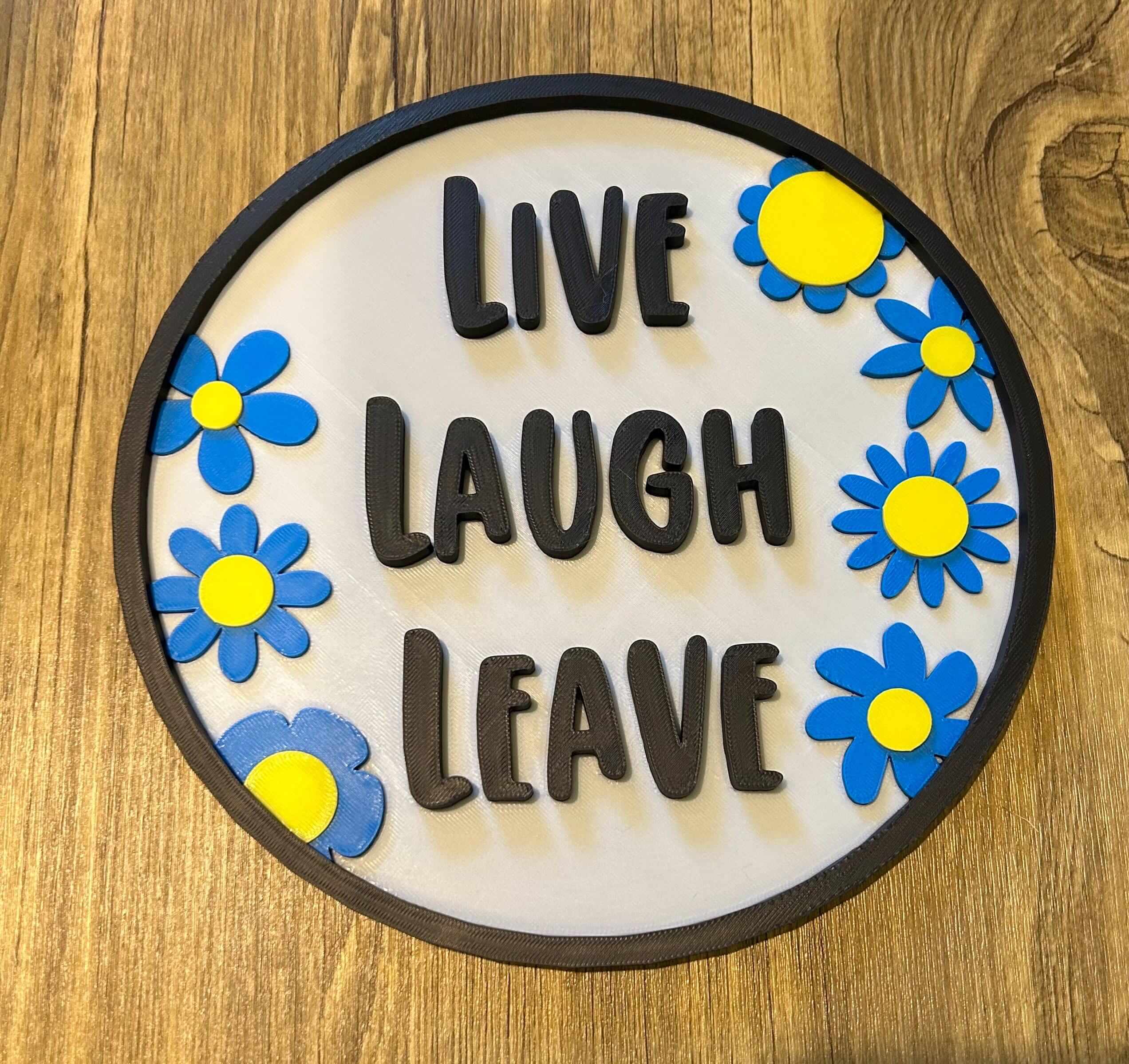 quirky door sign featuring the text 'Live Laugh Leave' with colorful flowers on a rustic background.