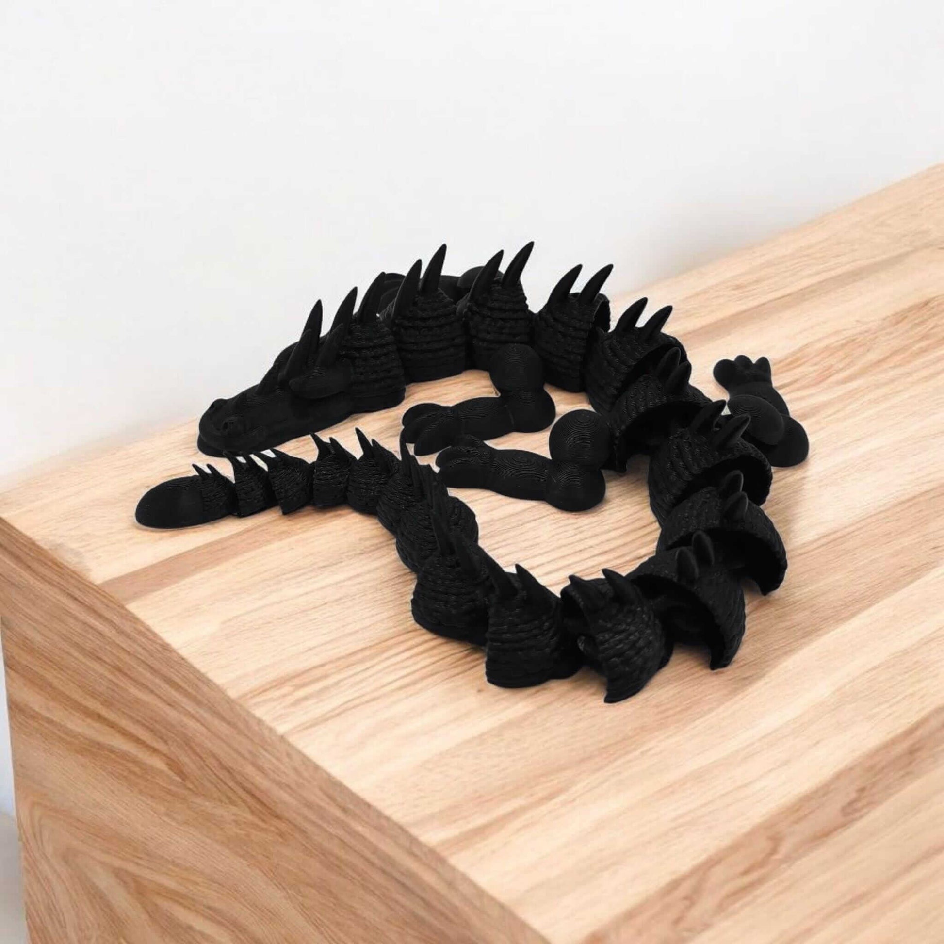 Articulated dragon fidget toy displayed on a wooden surface, designed for stress relief and fun fidgeting.