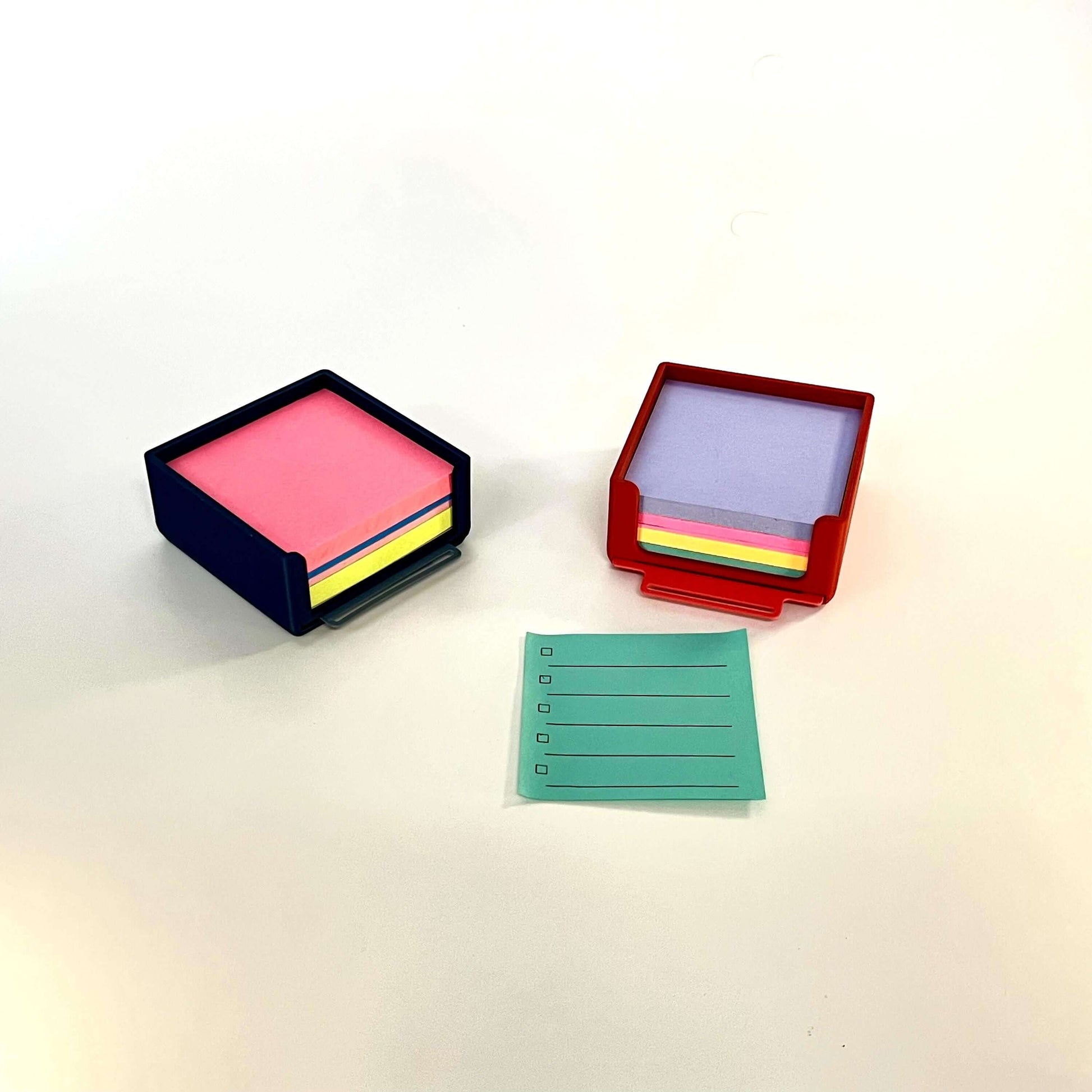 Post it holder organizer featuring pink and purple sticky notes with a blue and red holder on a workspace.