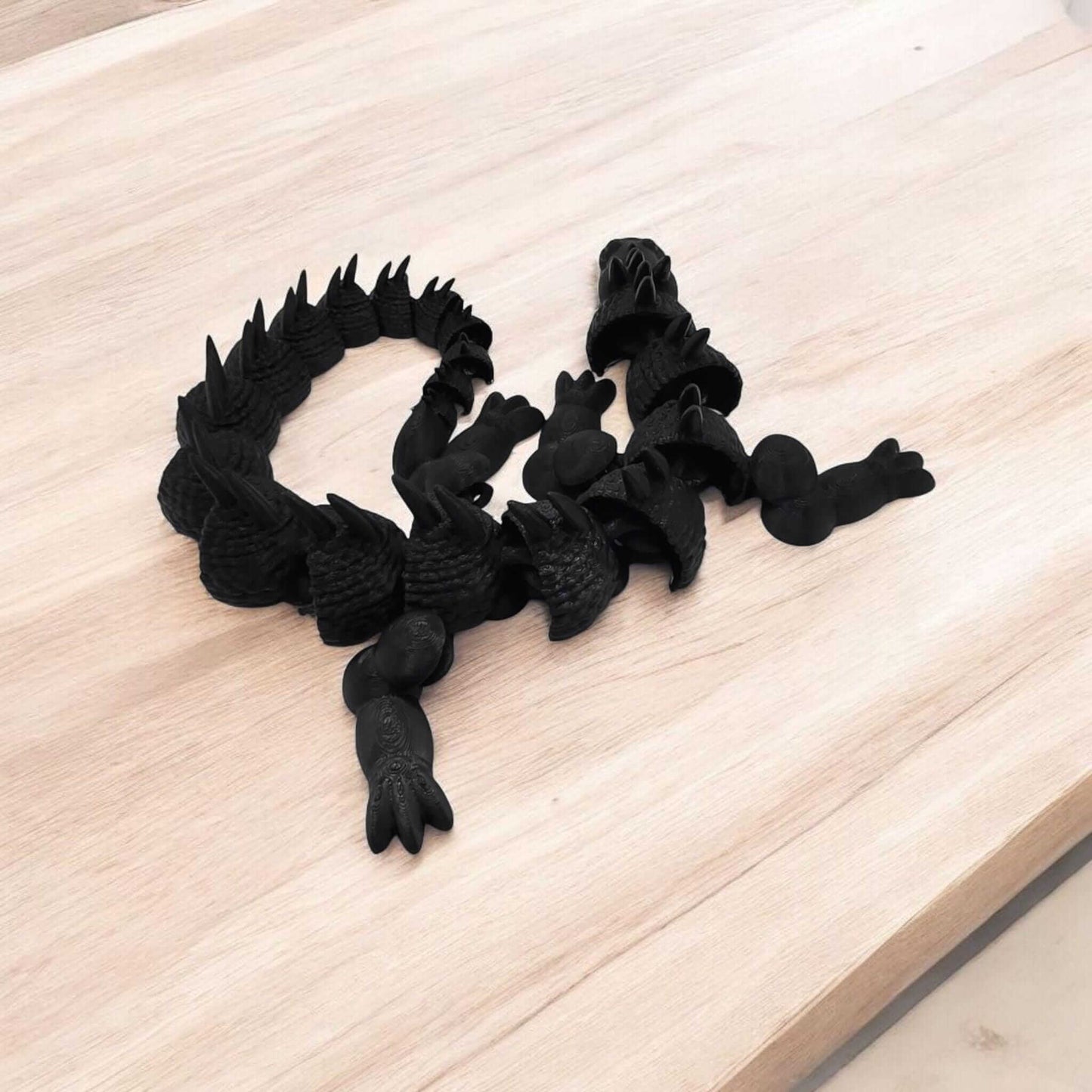 Articulated dragon fidget toy on a wooden surface, showcasing its intricate design and flexible joints.