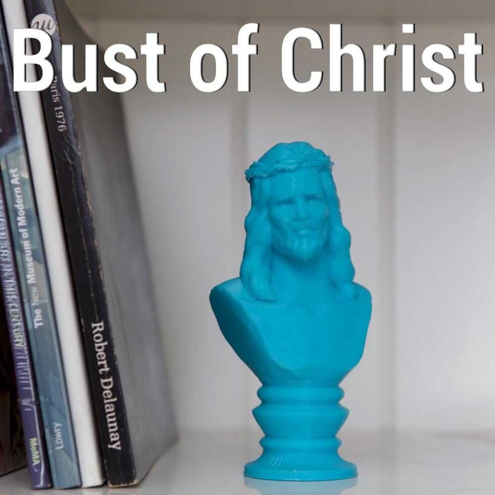 modern Christ bust sculpture displayed among books on a shelf with a blue finish.
