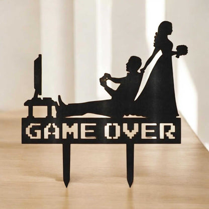 Funny gamer wedding cake topper featuring a groom playing video games and a bride pulling him away with 'GAME OVER' sign.