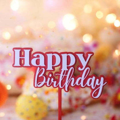 Elegant birthday cake topper featuring bold Happy Birthday text in red and white against a festive background.