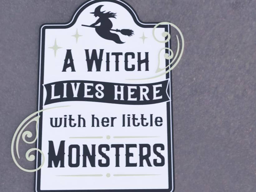 Halloween porch decor sign featuring a witch silhouette with the text 'A Witch Lives Here with Her Little Monsters'