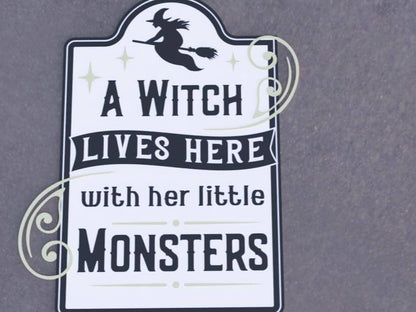 Halloween porch decor sign featuring a witch silhouette with the text 'A Witch Lives Here with Her Little Monsters'