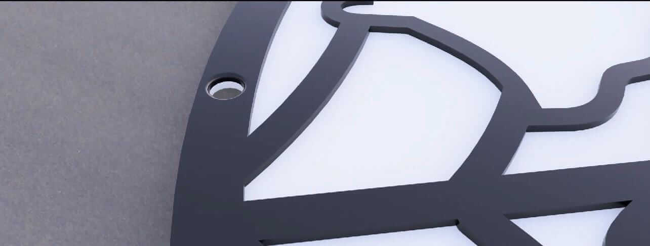 Close-up view of a Halloween wall decor sign showing the black design elements and mounting hole.